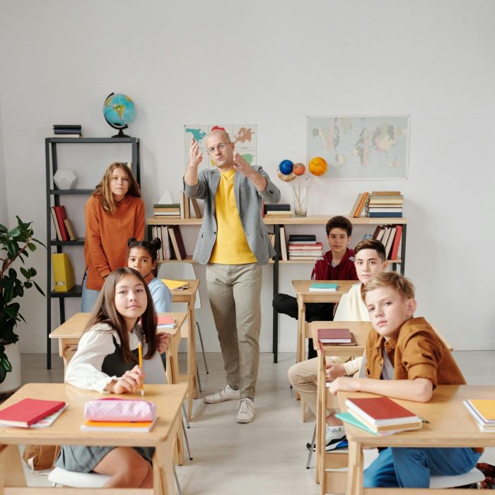 Teacher interacting with diverse group of students in modern classroom setting.